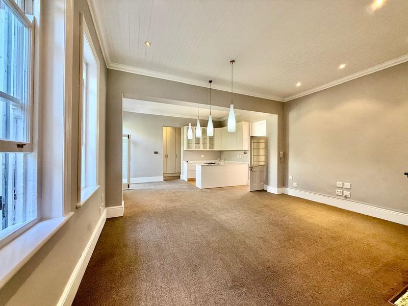 Spacious open-plan living and kitchen area featuring neutral tones, built-in cabinetry, kitchen island, and classic architectural details including crown molding and beadboard ceilings.