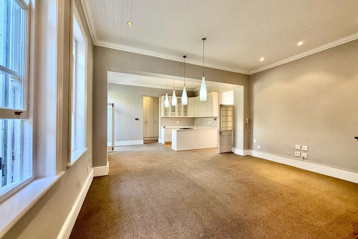 Spacious open-plan living and kitchen area featuring neutral tones, built-in cabinetry, kitchen island, and classic architectural details including crown molding and beadboard ceilings.