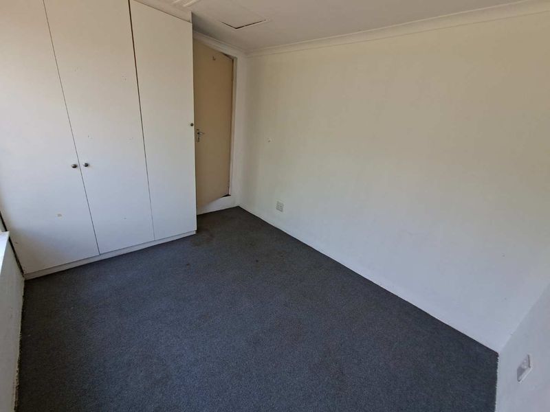 An empty bedroom featuring built-in cupboards, carpeted flooring, and neutral wall finishes, offering a blank canvas for personalization.