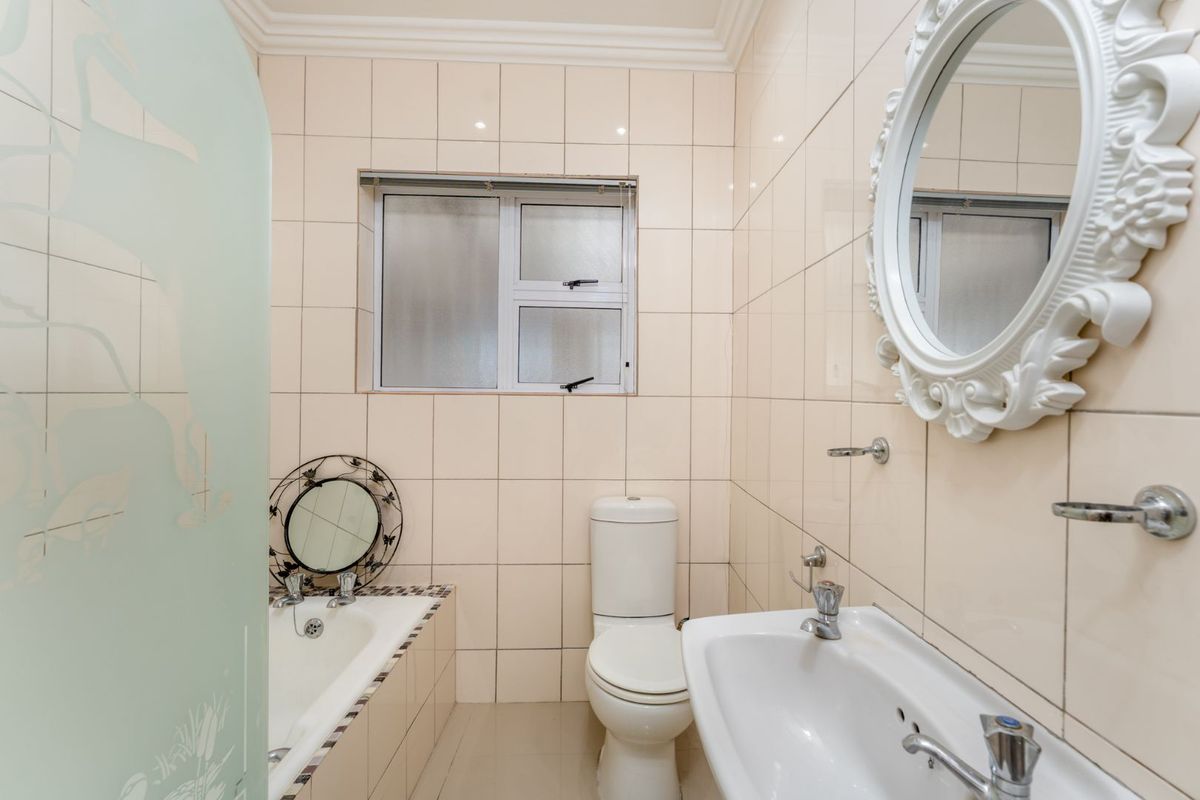 A functional bathroom featuring a built-in bathtub, a standard toilet, and a wall-mounted basin with tiled walls.