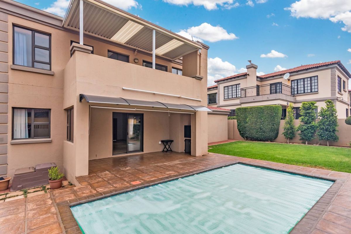 Rear view of the property featuring a covered patio, swimming pool with cover, and a landscaped garden area.