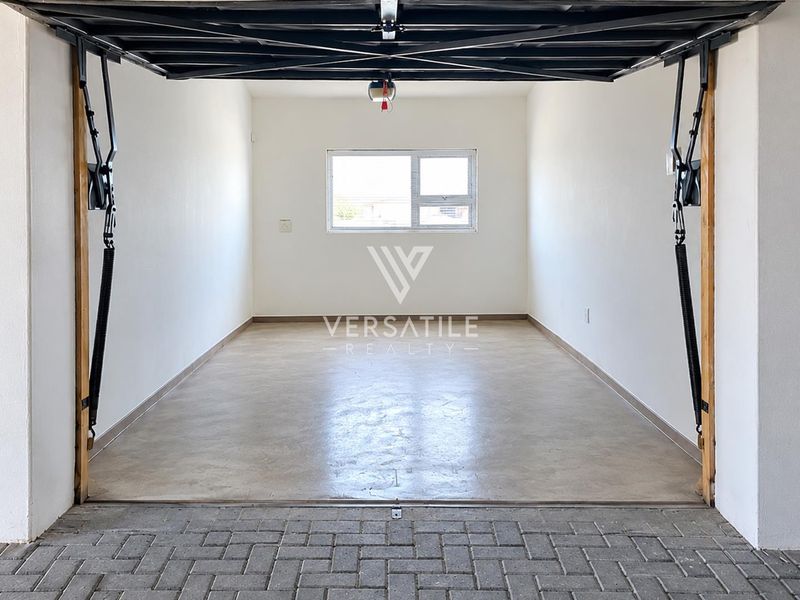 A clean, empty single-car garage featuring concrete flooring, a functional garage door mechanism, and a rear window for natural light.