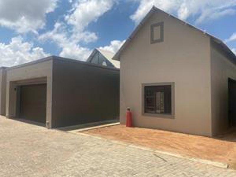 Front exterior view of a townhouse featuring a garage and paved driveway with unfinished landscaping.