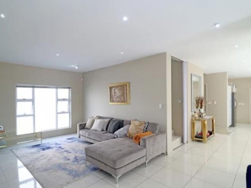 Spacious open-plan living area featuring neutral walls, modern tiled flooring, and recessed downlighting, creating a bright and cohesive flow throughout the home.
