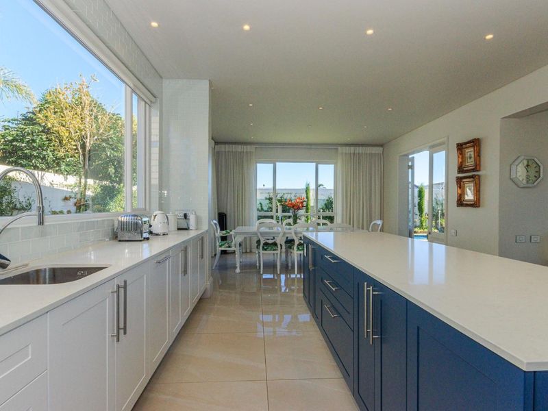 Modern open-plan kitchen featuring a large central island, quartz countertops, sleek cabinetry, and abundant natural light with views of the outdoor area.