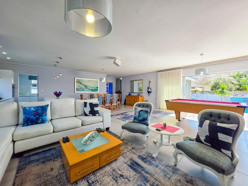 Spacious open-plan living and dining area featuring tiled floors, modern lighting, and large sliding doors providing seamless access to the outdoor pool area.