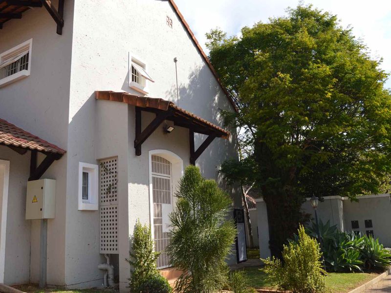 Front elevation of a house featuring a stucco facade, tiled roof, and a covered entrance with a timber awning.