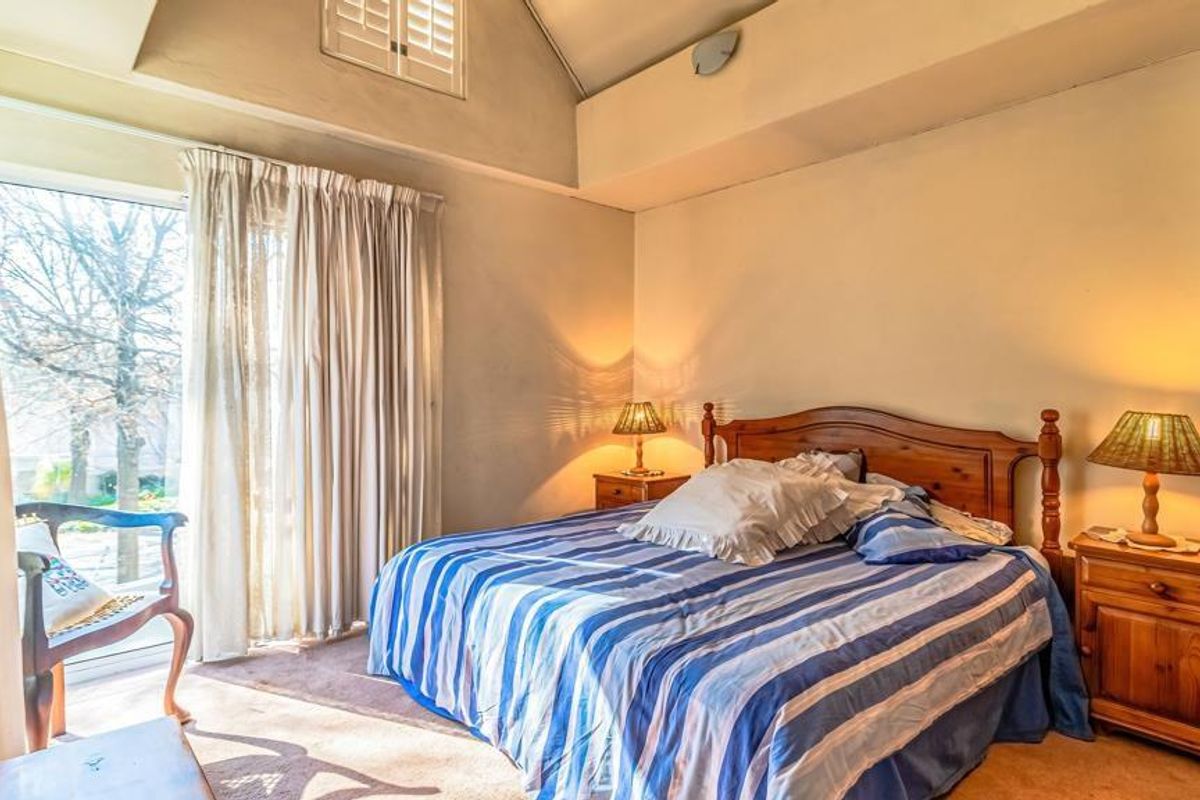 A bedroom featuring a vaulted ceiling, carpeted flooring, and a sliding glass door providing natural light and outdoor access.