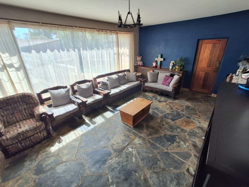 Living room featuring natural flagstone flooring, a dark blue accent wall, and a large window providing ample natural light.