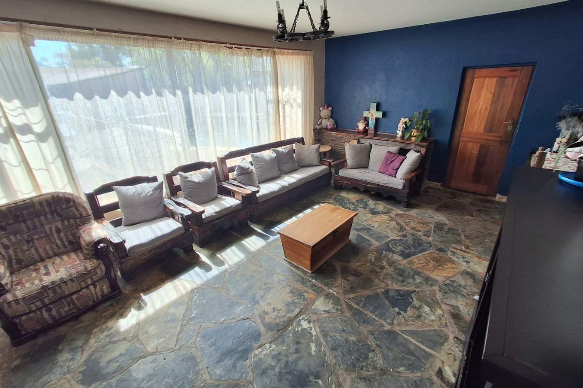 Living room featuring natural flagstone flooring, a dark blue accent wall, and a large window providing ample natural light.