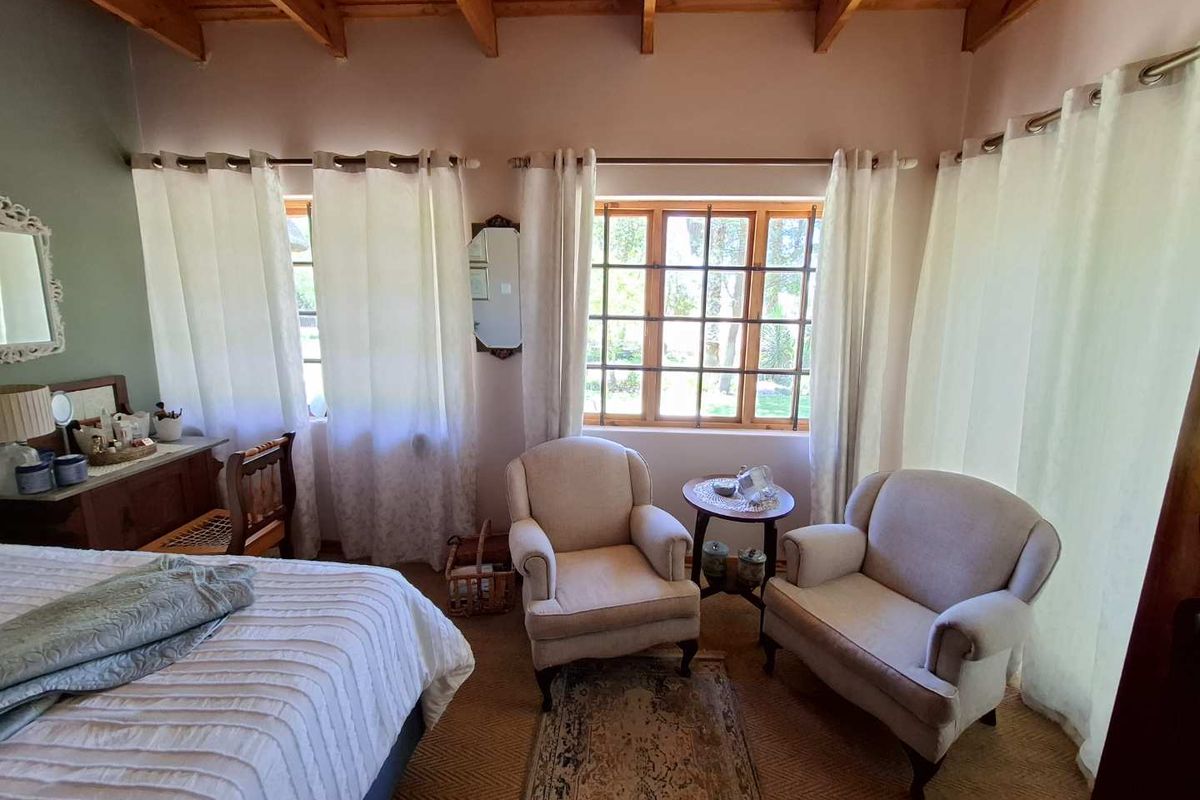 A cozy bedroom featuring exposed timber ceiling beams, large multi-pane windows, and neutral wall finishes, creating a warm and inviting atmosphere.