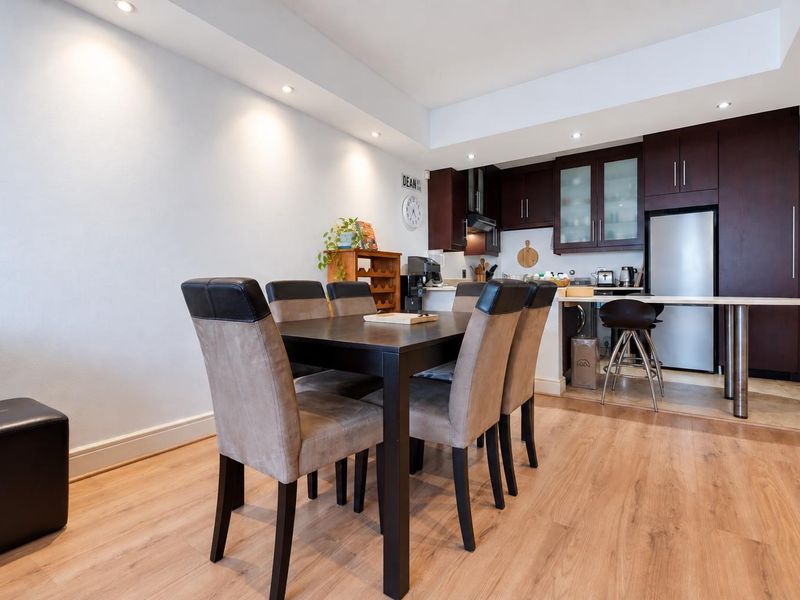 Open-plan living and dining area featuring a modern kitchen with dark wood cabinetry, recessed lighting, and laminate flooring throughout.