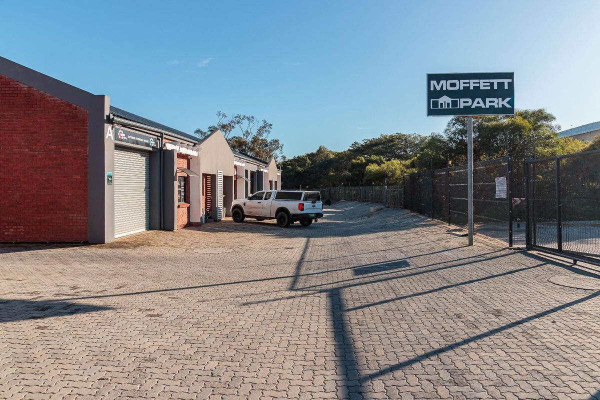 Front view of Moffett Park commercial property featuring paved driveway, brick facade buildings with roller shutter doors, and perimeter security fencing.