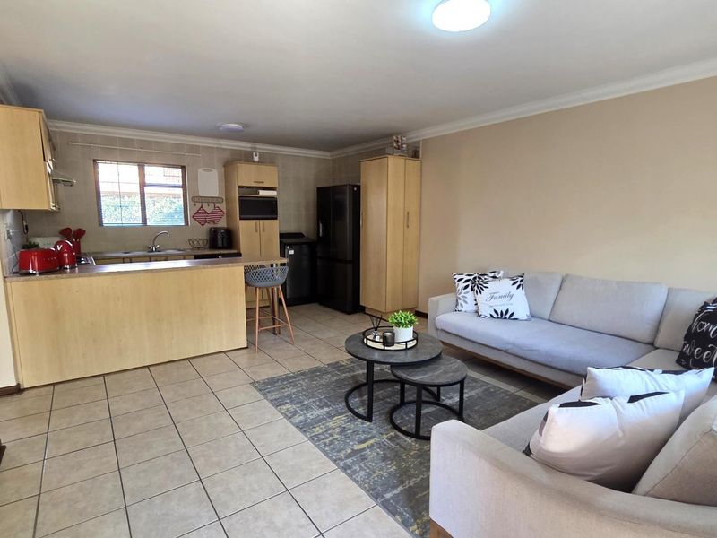 An open-plan living area featuring a functional kitchen with built-in cabinetry and a breakfast counter, seamlessly flowing into a comfortable lounge space.