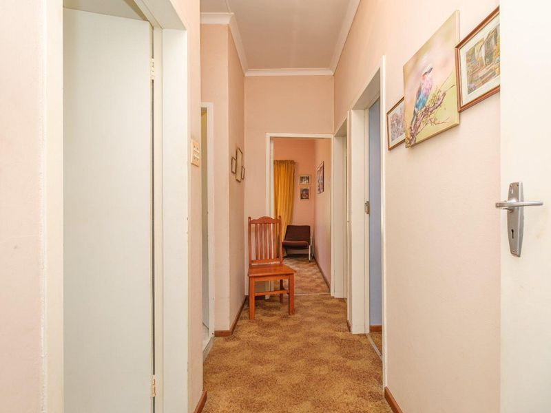 A functional residential hallway featuring carpeted flooring, coving, and multiple internal door access points.
