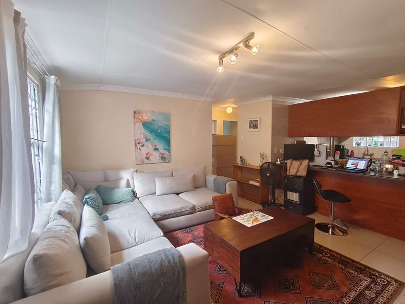 Open-plan living area featuring tiled flooring, a wooden breakfast bar, and coved ceilings, creating a functional combined kitchen and lounge space.