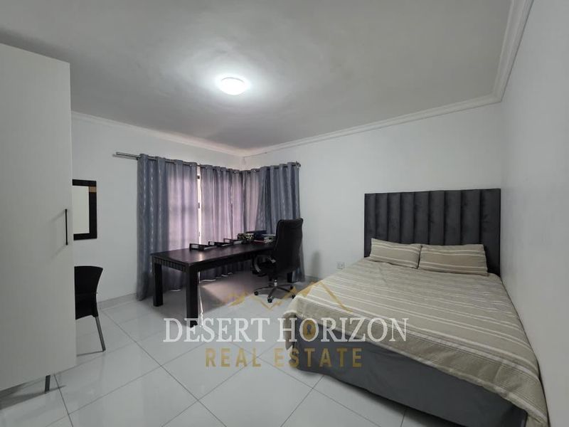 A well-maintained bedroom featuring tiled flooring, a built-in wardrobe, and neutral wall finishes, providing a clean and functional living space.