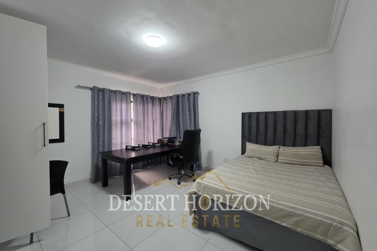 A well-maintained bedroom featuring tiled flooring, a built-in wardrobe, and neutral wall finishes, providing a clean and functional living space.