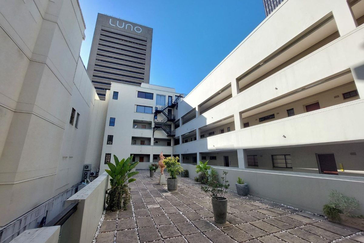 An elevated view of an apartment complex courtyard featuring a paved terrace area and external fire escape access.