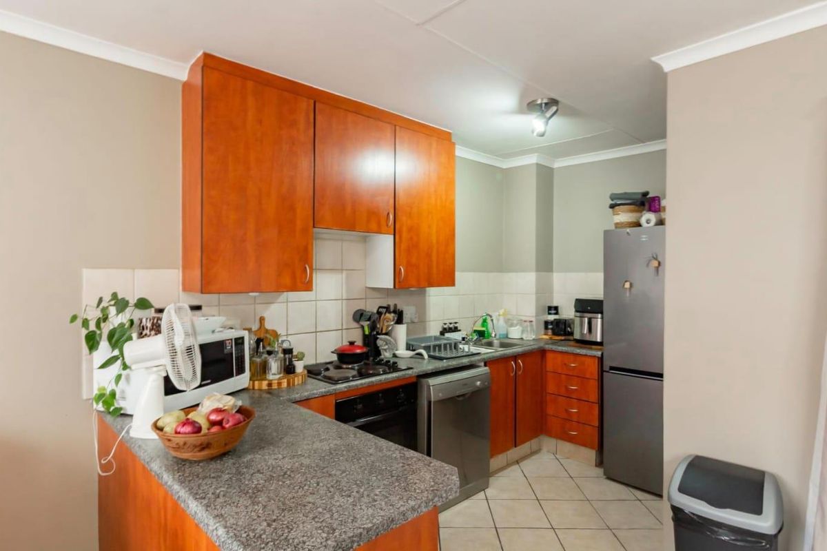 Functional kitchen featuring wood-finish cabinetry, granite-look countertops, built-in oven, gas hob, and tiled flooring in a practical layout.
