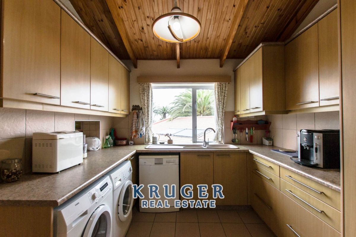 A functional kitchen featuring wood-paneled ceilings, laminate cabinetry, tiled flooring, and a double sink with a window view.