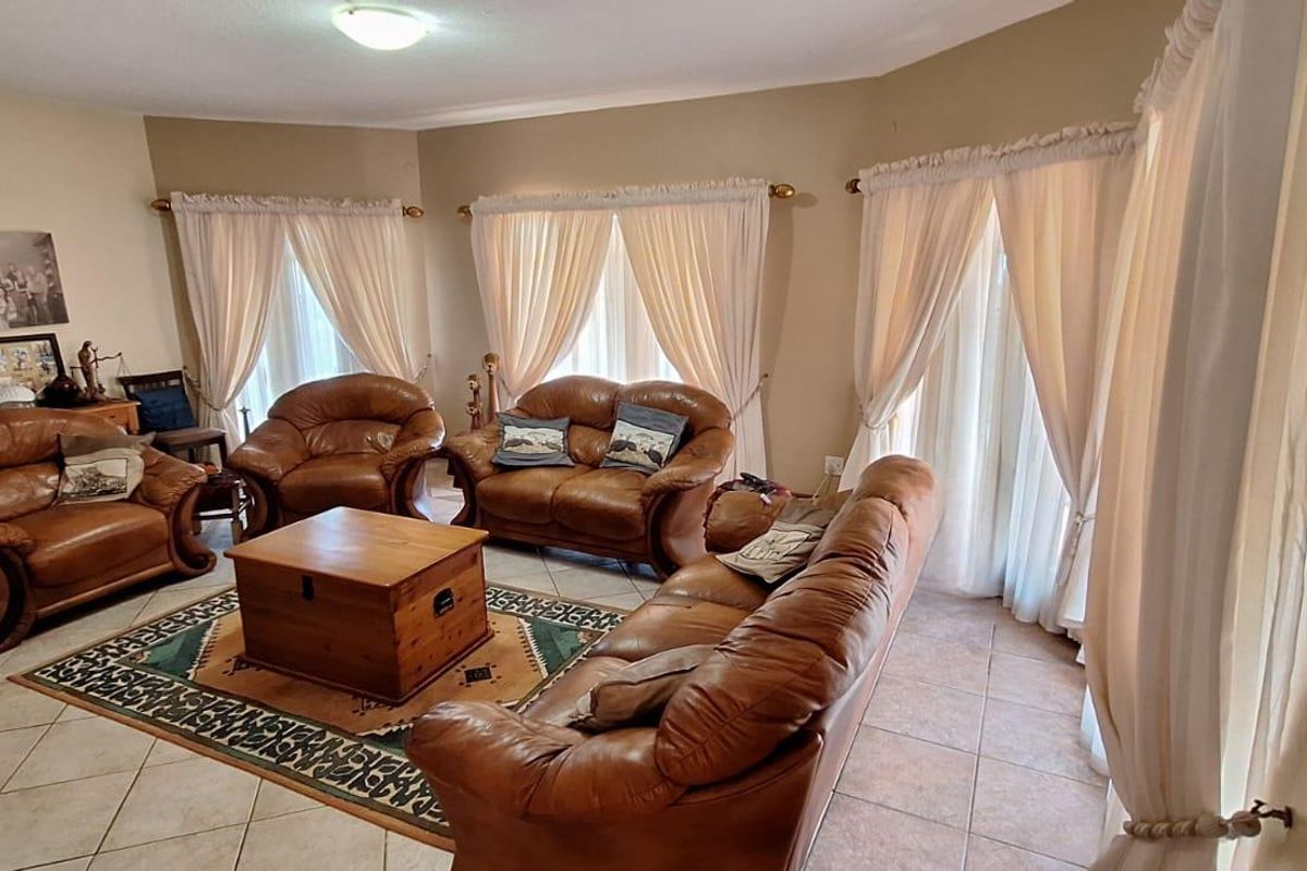 A spacious living room featuring tiled flooring and large windows with curtains, providing a comfortable and well-lit area for relaxation.