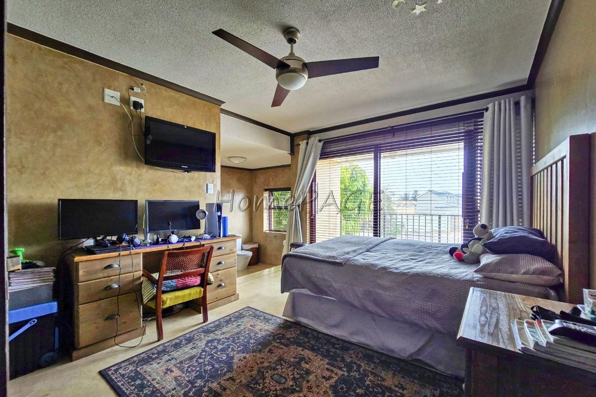 A bedroom featuring a ceiling fan, large sliding glass doors with blinds, and an integrated en-suite bathroom area.