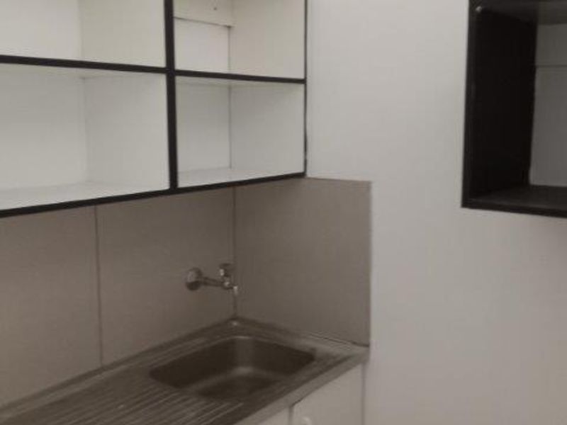 A compact kitchenette area featuring a stainless steel sink, built-in cabinetry, and basic splashback, suitable for a small office utility space.