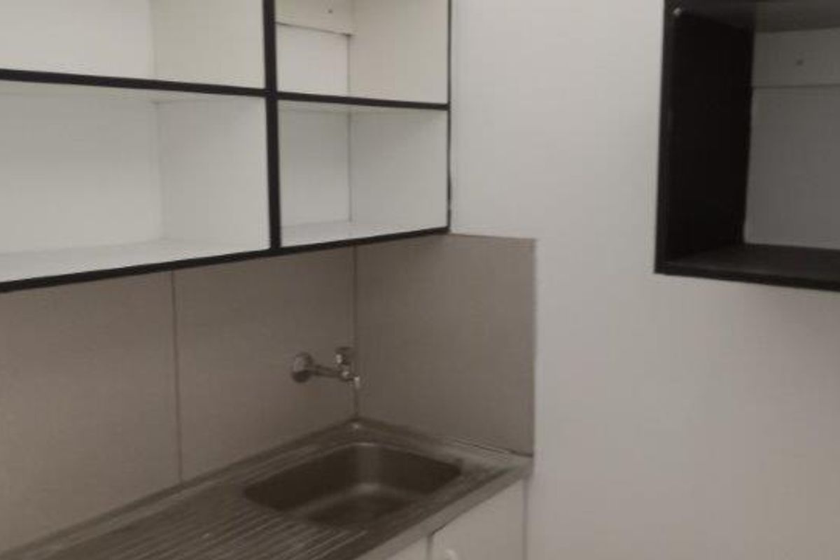 A compact kitchenette area featuring a stainless steel sink, built-in cabinetry, and basic splashback, suitable for a small office utility space.