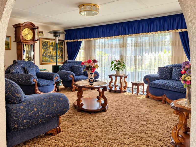 A spacious living room featuring large windows with floor-to-ceiling curtains and a central ceiling light fixture.