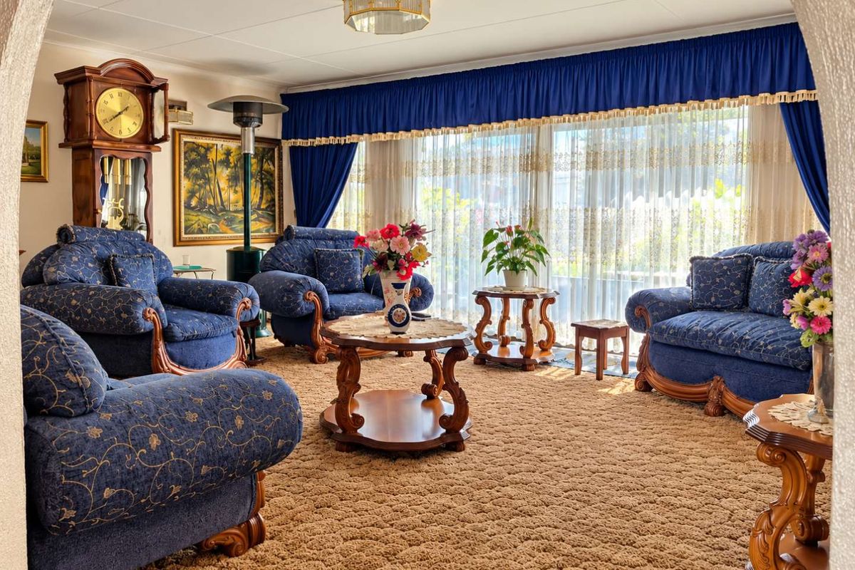 A spacious living room featuring large windows with floor-to-ceiling curtains and a central ceiling light fixture.