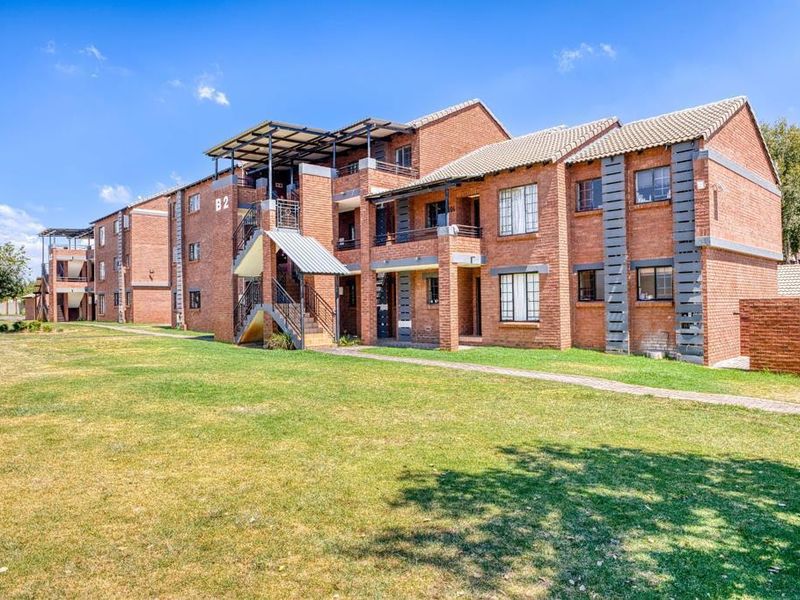 A view of the apartment complex exterior featuring face brick construction, tiled roofing, and communal landscaped grounds.