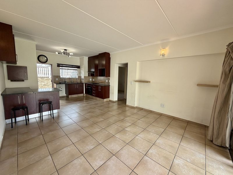 Open-plan living area featuring a kitchen with dark wood cabinetry, built-in appliances, and tiled flooring throughout the space.