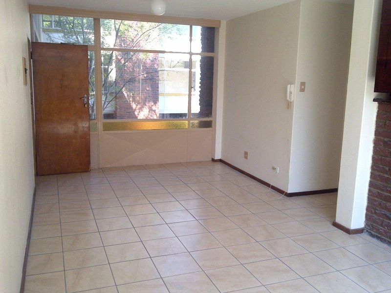 An empty living room featuring tiled flooring, a brick fireplace, and a large window panel with an integrated timber door.