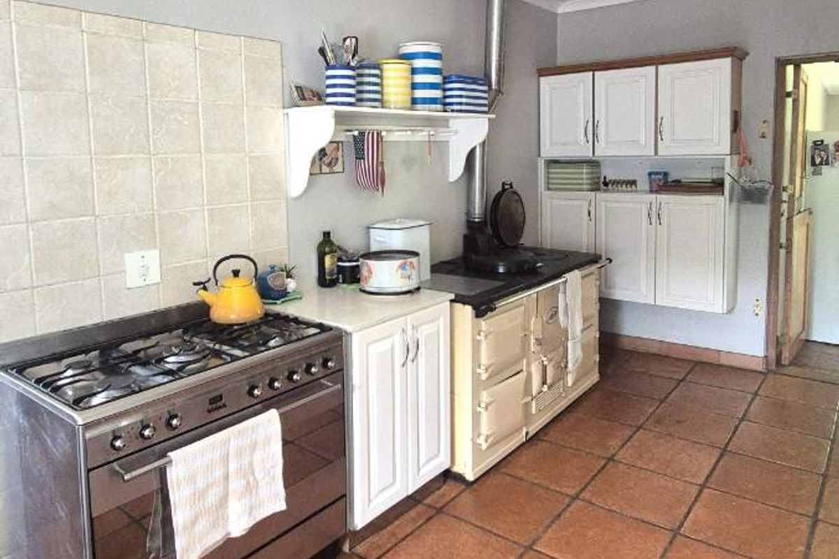 A functional kitchen featuring a gas stove, built-in cabinetry, and traditional terracotta floor tiles, offering a practical layout for daily cooking and preparation.