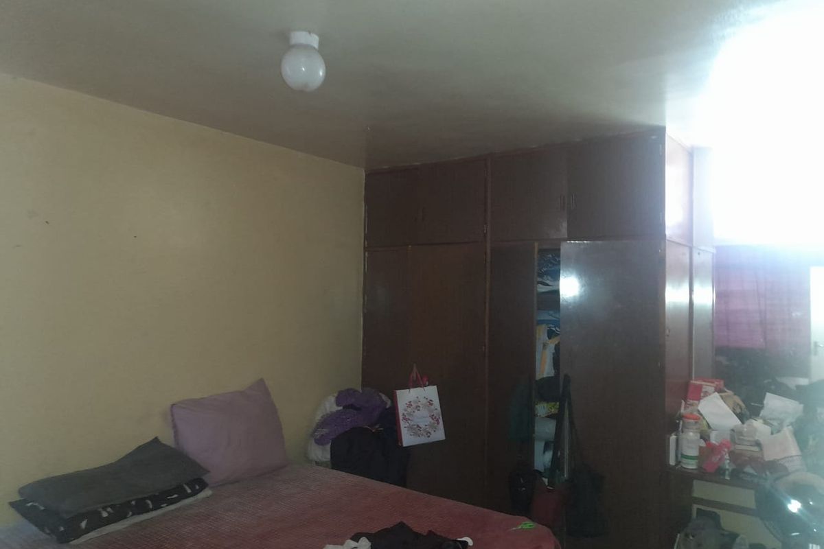 A bedroom featuring built-in floor-to-ceiling wooden cupboards providing ample storage space.