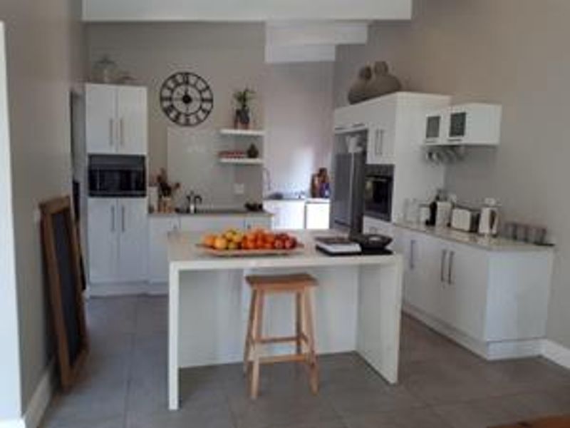 Modern kitchen featuring white cabinetry, a central island, built-in oven and microwave, and tiled flooring.