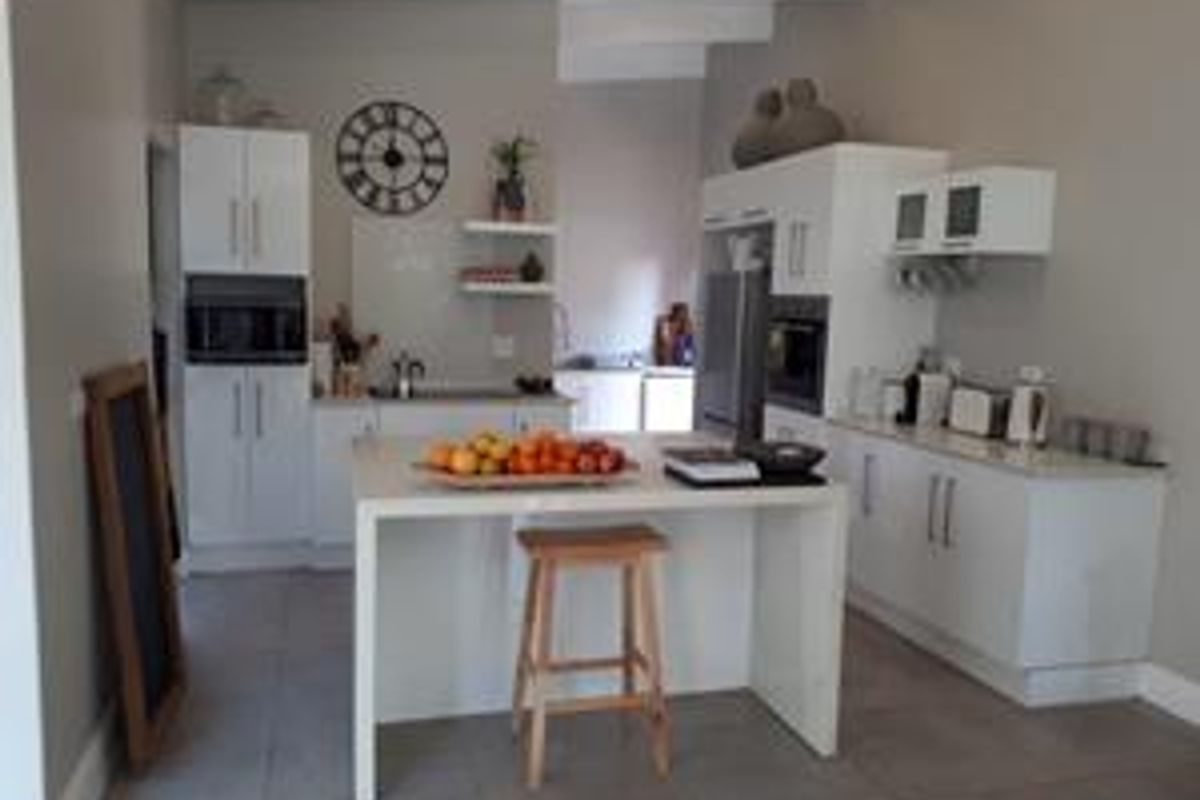 Modern kitchen featuring white cabinetry, a central island, built-in oven and microwave, and tiled flooring.