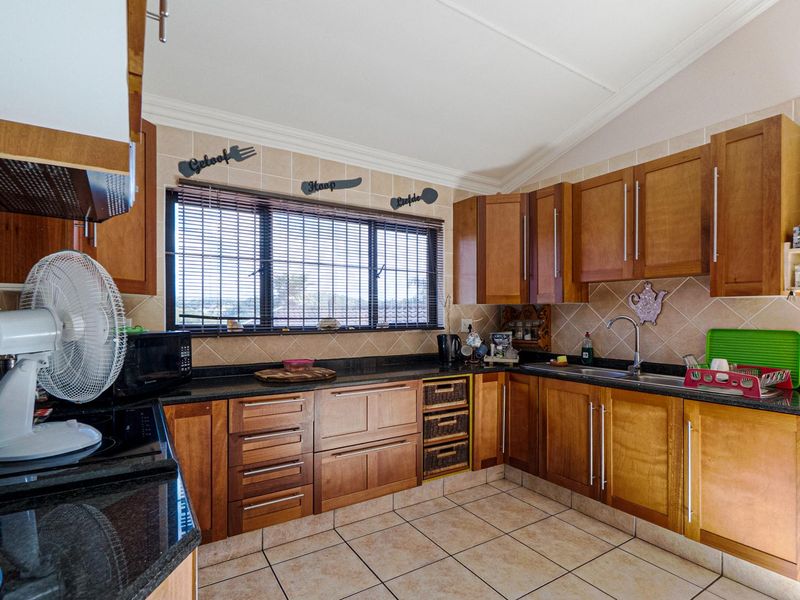 A functional kitchen featuring wooden cabinetry, granite countertops, tiled backsplash, and ceramic flooring, offering a classic layout with ample storage space.