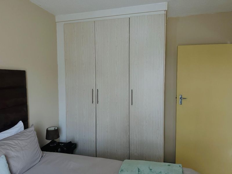 A bedroom featuring a light wood-grain built-in wardrobe and a solid internal door, providing functional storage and access.