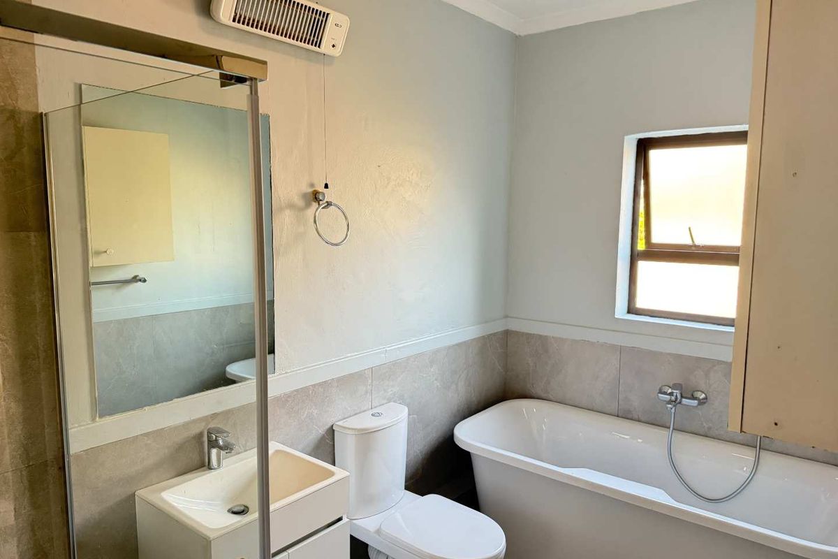 A functional bathroom featuring a freestanding bathtub, a vanity unit with a mirror, a toilet, and a separate shower enclosure with tiled finishes.