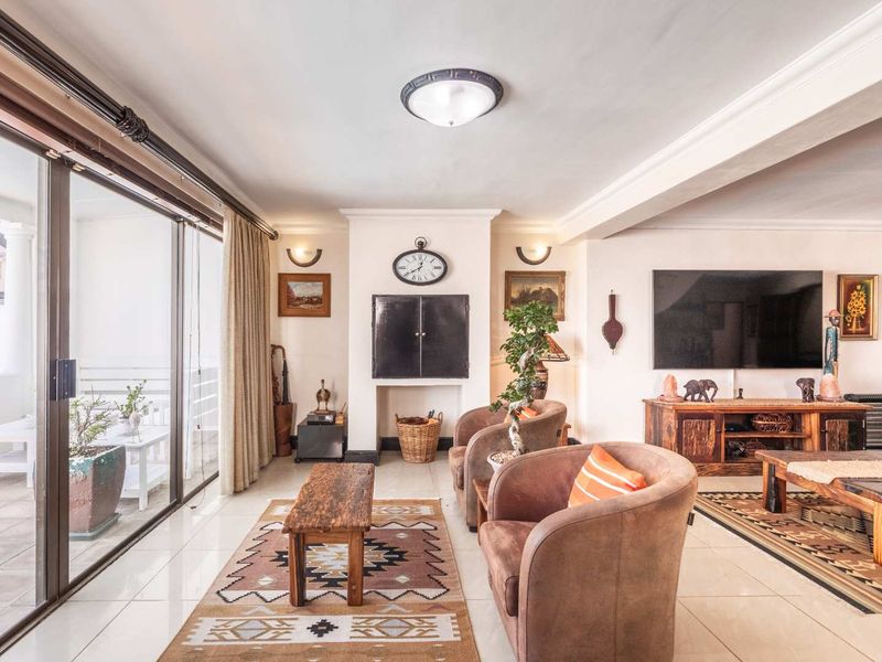 Spacious living room featuring large sliding glass doors leading to a patio, tiled flooring, and a central fireplace feature.