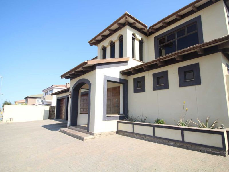 A well-maintained double-storey residential property featuring a paved driveway, covered entrance, and distinctive architectural detailing with exposed rafter tails.