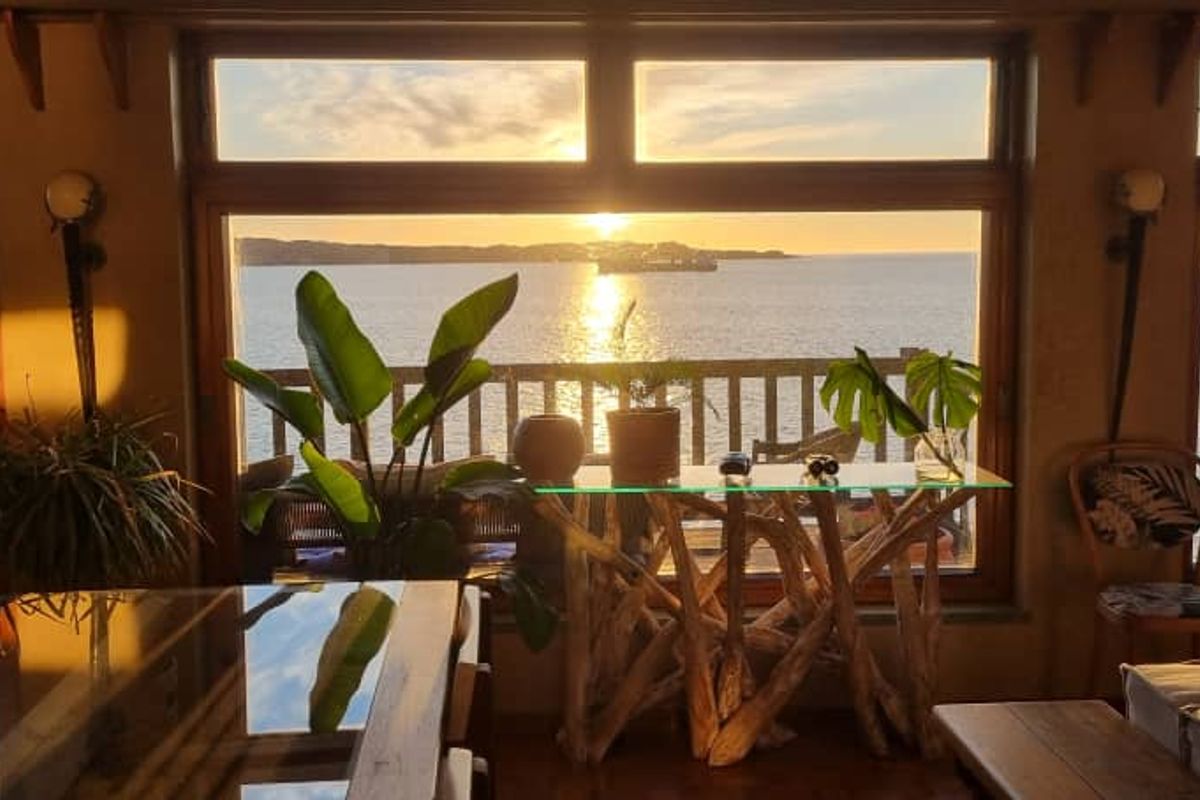 Spacious living area featuring expansive windows with panoramic ocean views and direct access to an outdoor deck.