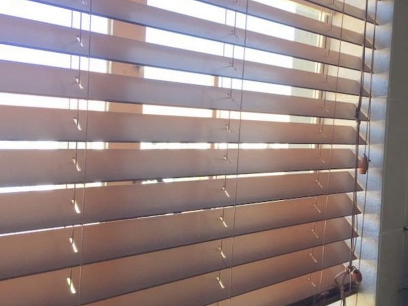 A close-up view of wooden venetian blinds installed on a kitchen window.
