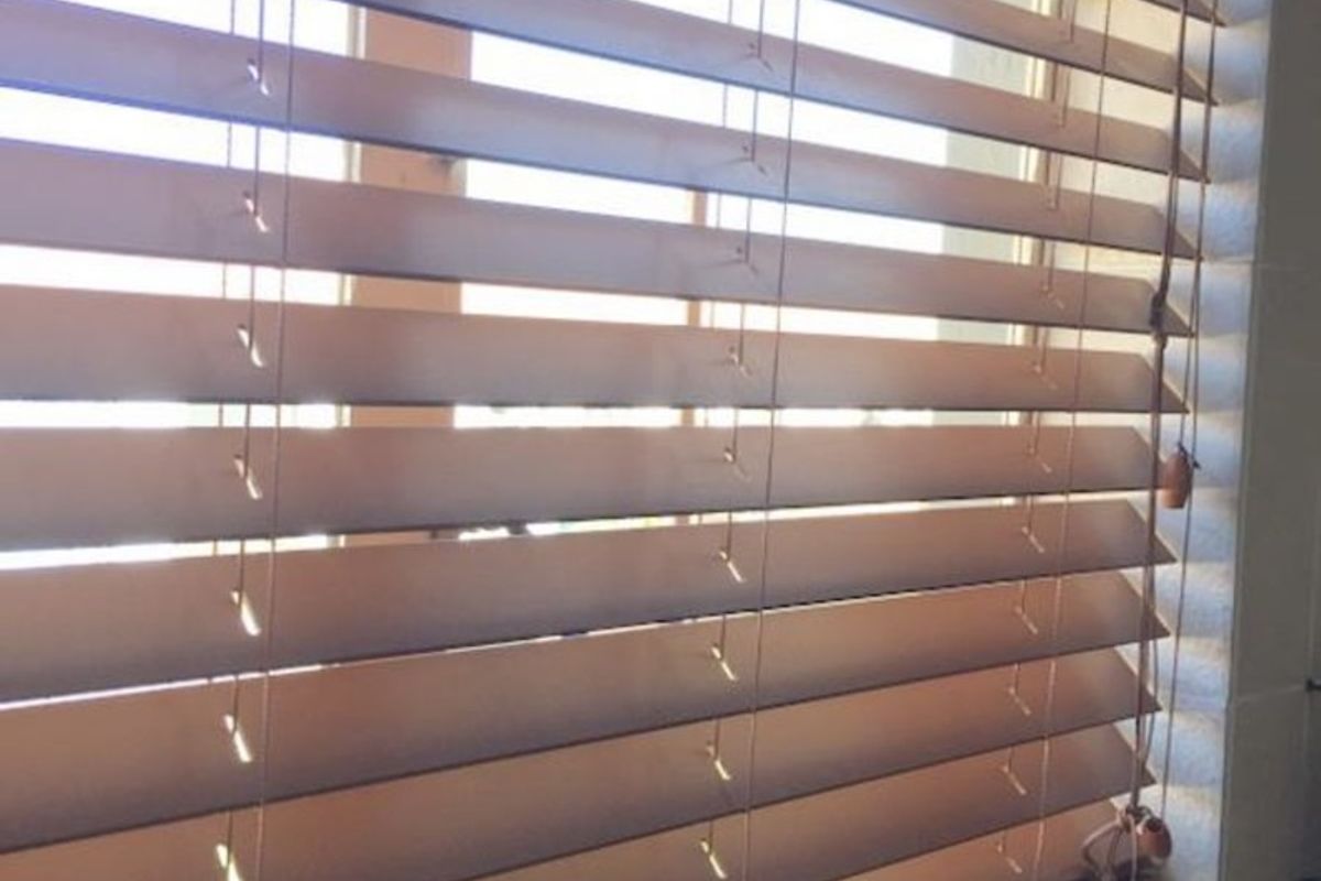A close-up view of wooden venetian blinds installed on a kitchen window.