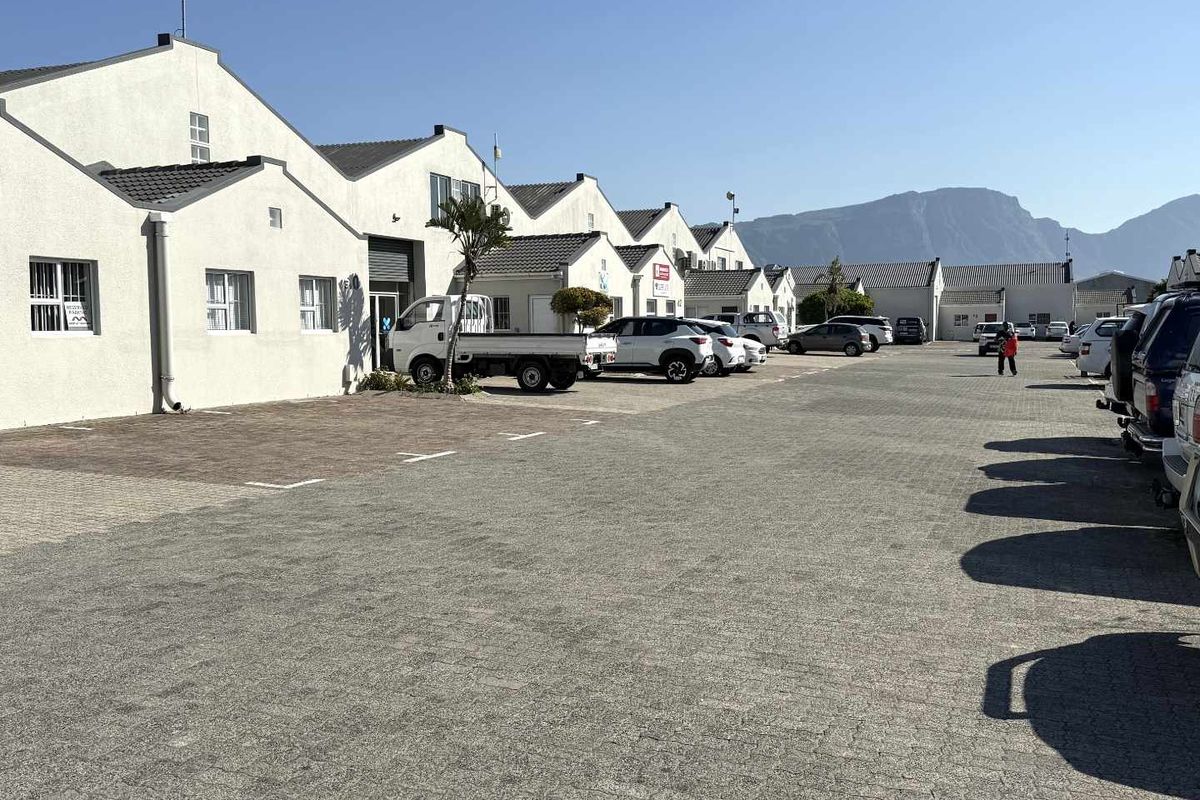Exterior view of a mixed-use commercial property complex featuring a paved parking area and multiple units with pitched roofs.