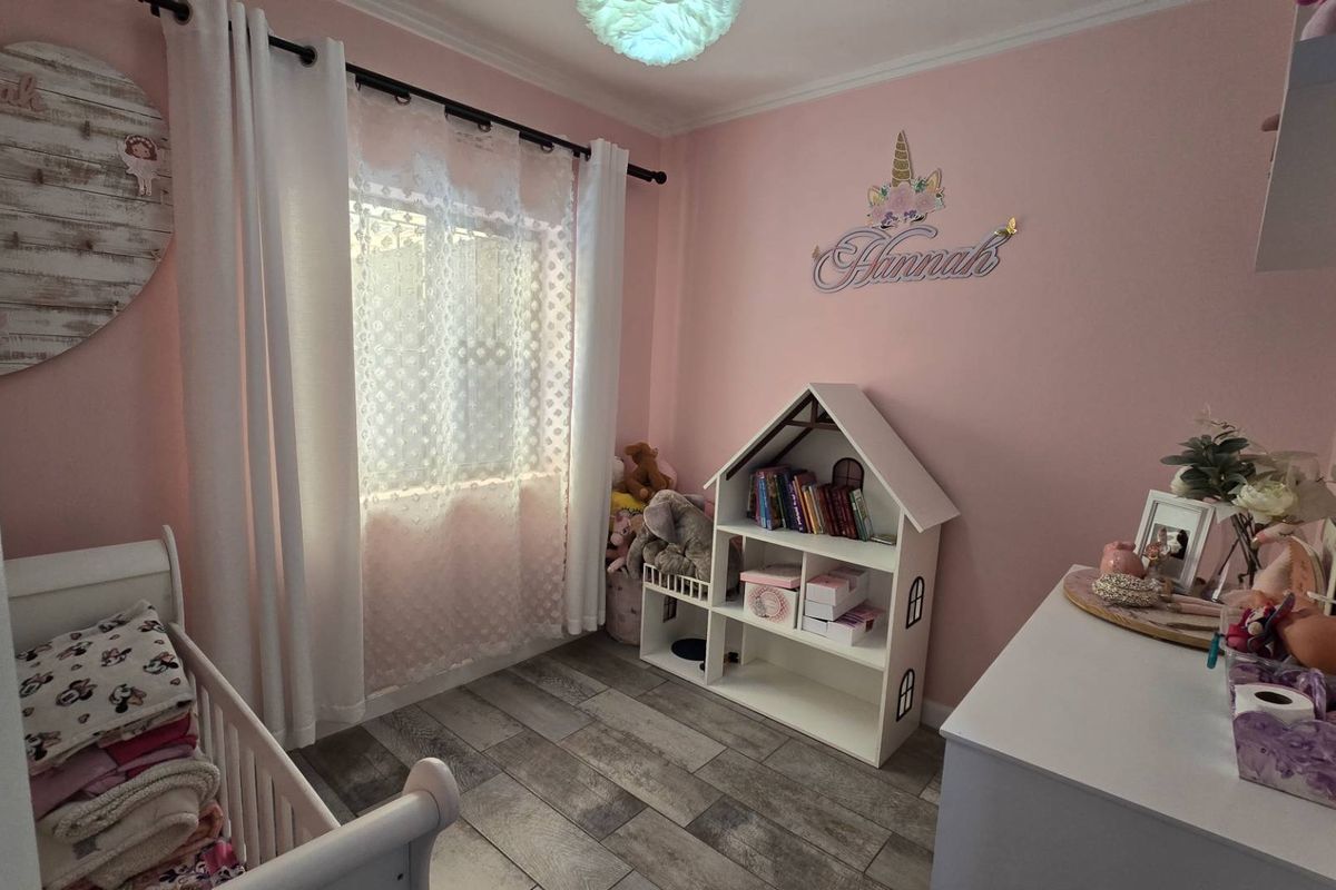 A cozy bedroom featuring tiled flooring, pink painted walls, and a window with curtain fixtures.
