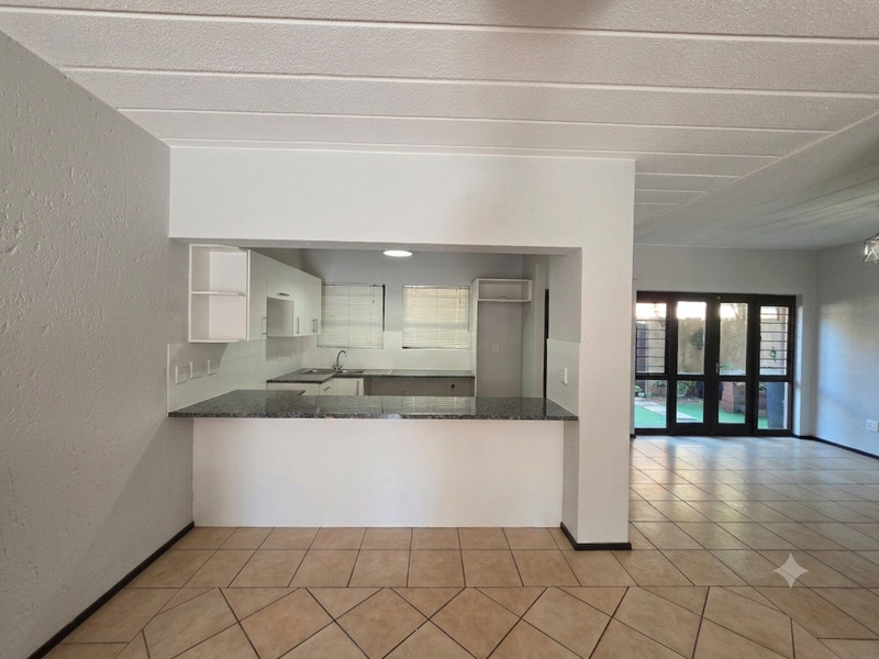 Open plan kitchen and living area featuring granite countertops, tiled flooring, and direct access to the rear garden through glass french doors.