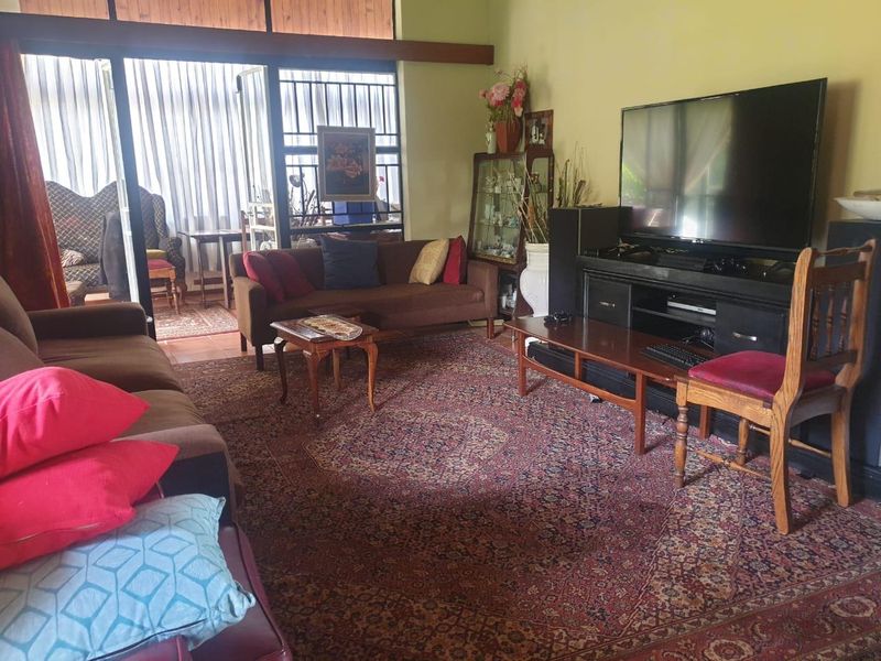 A spacious living room featuring timber ceiling beams and large sliding glass doors that provide access to an adjoining patio area.